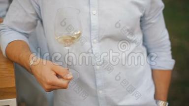 男人在透明的酒杯里摇白酒。 一个人品尝着一杯白酒..